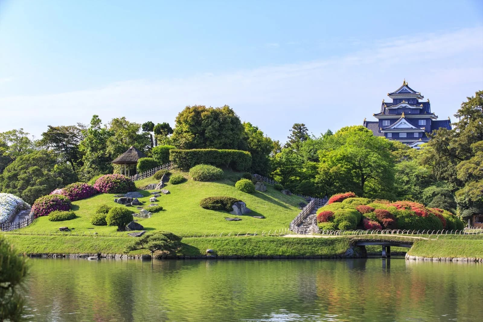 芝生の丘と池のある岡山後楽園の庭園と、奥に見える岡山城